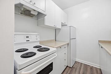 Hamilton apartment for rent - A white stove with four burners is in a kitchen with white cabinets.