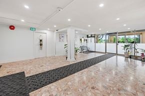 Hamilton apartment for rent - A hallway with a marble floor and a red fire alarm on the wall.