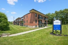 Kitchener apartment for rent - A blue sign stands in front of a brick building.