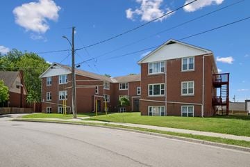 Kitchener apartment for rent - A red brick apartment building with a white roof and a balcony on the second floor.