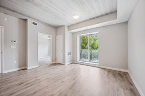 Kitchener apartment for rent - A spacious room with wooden floors and a large window.