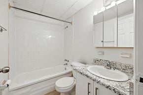 Hamilton apartment for rent - A white bathroom with a marble counter top and a white bathtub.