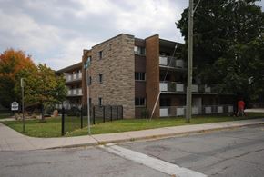 Hamilton apartment for rent - A large building with a stone facade sits on a street corner.