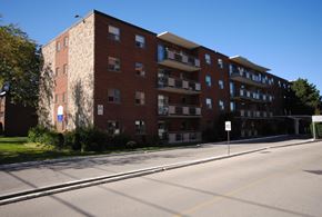 Stoney Creek apartment for rent - A large red brick apartment building with a white sign on the right side.
