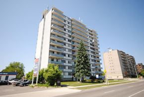 Hamilton apartment for rent - A tall residential building with a parking lot in front.