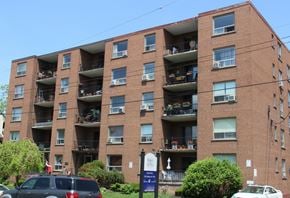 Hamilton apartment for rent - A large brick building with balconies and cars parked in front.