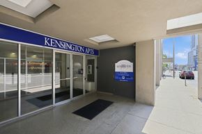 Hamilton apartment for rent - The image shows the entrance to Kensington Apartments with a blue signboard and a glass door.