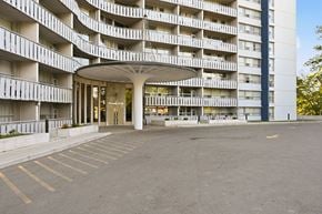 Hamilton apartment for rent - A large parking lot in front of a white building with a lot of windows.