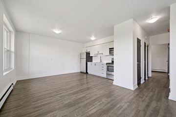 Kitchener apartment for rent - A spacious kitchen with white cabinets and a wooden floor.