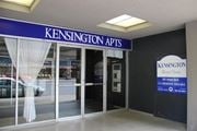 Hamilton apartment for rent - The image shows the front of Kensington Apts with a blue signboard and a window with white curtains.