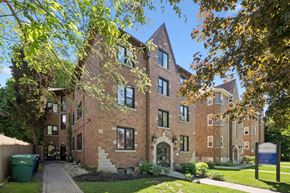 Kitchener apartment for rent - A large brick building with a green trash can in front.