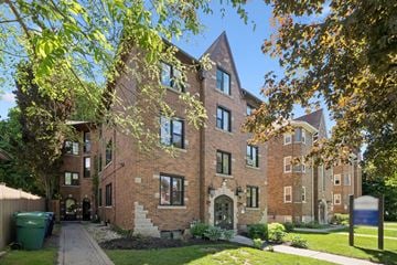 Kitchener apartment for rent - A large brick building with a green trash can in front.