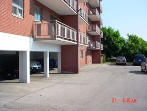 Hamilton apartment for rent - A parking lot in front of a red brick building with cars parked.