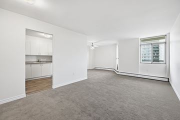Hamilton apartment for rent - A spacious, empty room with a window and a built-in cabinet.