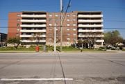 Hamilton apartment for rent - A large red and brown building with a parking lot in front.
