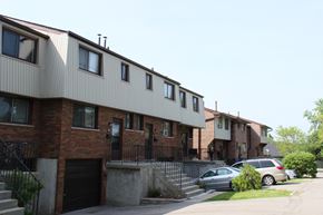 Hamilton apartment for rent - A row of townhouses with garages and cars parked in front.