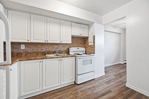 Hamilton apartment for rent - A kitchen with white cabinets and a brick backsplash.