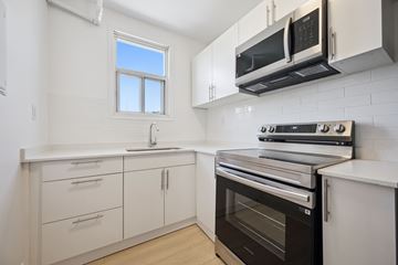 Kitchener apartment for rent - A kitchen with white cabinets and black appliances.