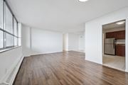Kitchener apartment for rent - A spacious room with wooden floors and white walls.