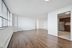 Kitchener apartment for rent - A spacious room with wooden floors and white walls.