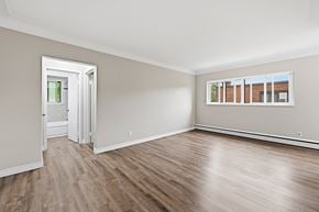 Hamilton apartment for rent - A room with wooden floors and a window showing a view of a building.