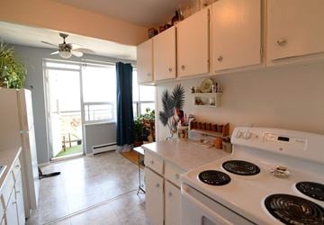 Hamilton apartment for rent - A white stove top oven with four burners is in a kitchen with white cabinets.