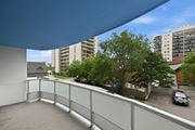 Hamilton apartment for rent - A balcony with a glass railing overlooks a parking lot and buildings.