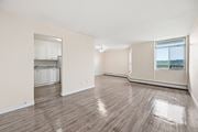 Hamilton apartment for rent - A spacious room with wooden flooring and a kitchen area in the background.