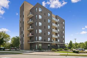 Kitchener apartment for rent - A modern apartment building with balconies and a black fence in front.