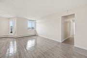 Hamilton apartment for rent - A spacious room with wooden flooring and a view of the outside through a large window.
