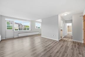 Hamilton apartment for rent - A spacious room with light wood flooring and large windows.