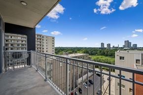 Kitchener apartment for rent - Balcony with a metal railing overlooks a parking lot and buildings.