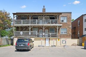 Kitchener apartment for rent - A grey car is parked in a parking lot in front of a wooden building.