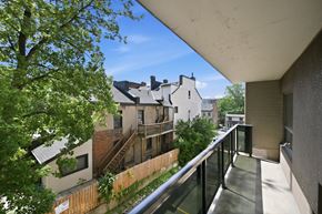 Hamilton apartment for rent - A balcony with a metal railing overlooks a tree and a building.