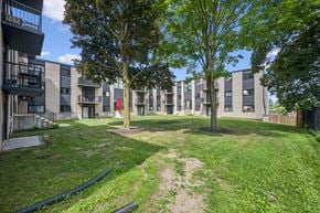 Waterloo apartment for rent - A grassy area in front of apartment buildings with a tree in the center.
