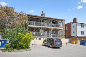 Kitchener apartment for rent - A parking lot with a car and a building with a balcony.