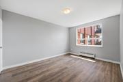 Hamilton apartment for rent - A room with wooden floors and a window showing a view of a building.