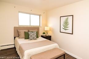 Welland apartment for rent - A bedroom with a bed, nightstand, and a framed leaf picture on the wall.