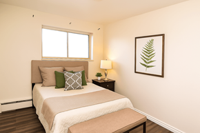 Welland apartment for rent - A bedroom with a bed, nightstand, and a framed leaf picture on the wall.