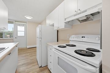 Stoney Creek apartment for rent - A white stove with four burners is in a kitchen with white cabinets.