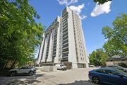 Kitchener apartment for rent - A tall white building with a parking lot in front of it.
