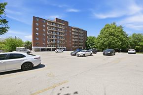 Hamilton apartment for rent - A parking lot with cars and a building in the background.