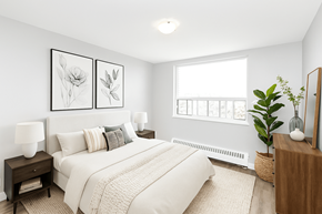 Hamilton apartment for rent - A bedroom with a large bed, two lamps, and a plant.