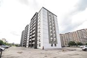Hamilton apartment for rent - A large, modern building with a lot of windows and a parking lot in front.