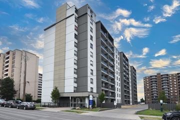 Hamilton apartment for rent - A large, modern apartment building with a parking lot in front.