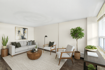 Hamilton apartment for rent - A living room with a grey couch, a wooden coffee table, a chair, a potted plant, and a painting on the wall.