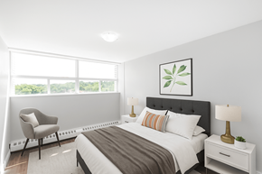 Dundas apartment for rent - A bedroom with a large bed, a chair, and a window.