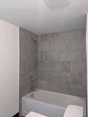 Cambridge apartment for rent - A white bathtub with a grey tile wall behind it.