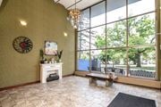 St. Catharines apartment for rent - A room with a fireplace, a chandelier, and a large window overlooking a park.