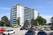 St. Catharines apartment for rent - A parking lot with cars and a large white building in the background.